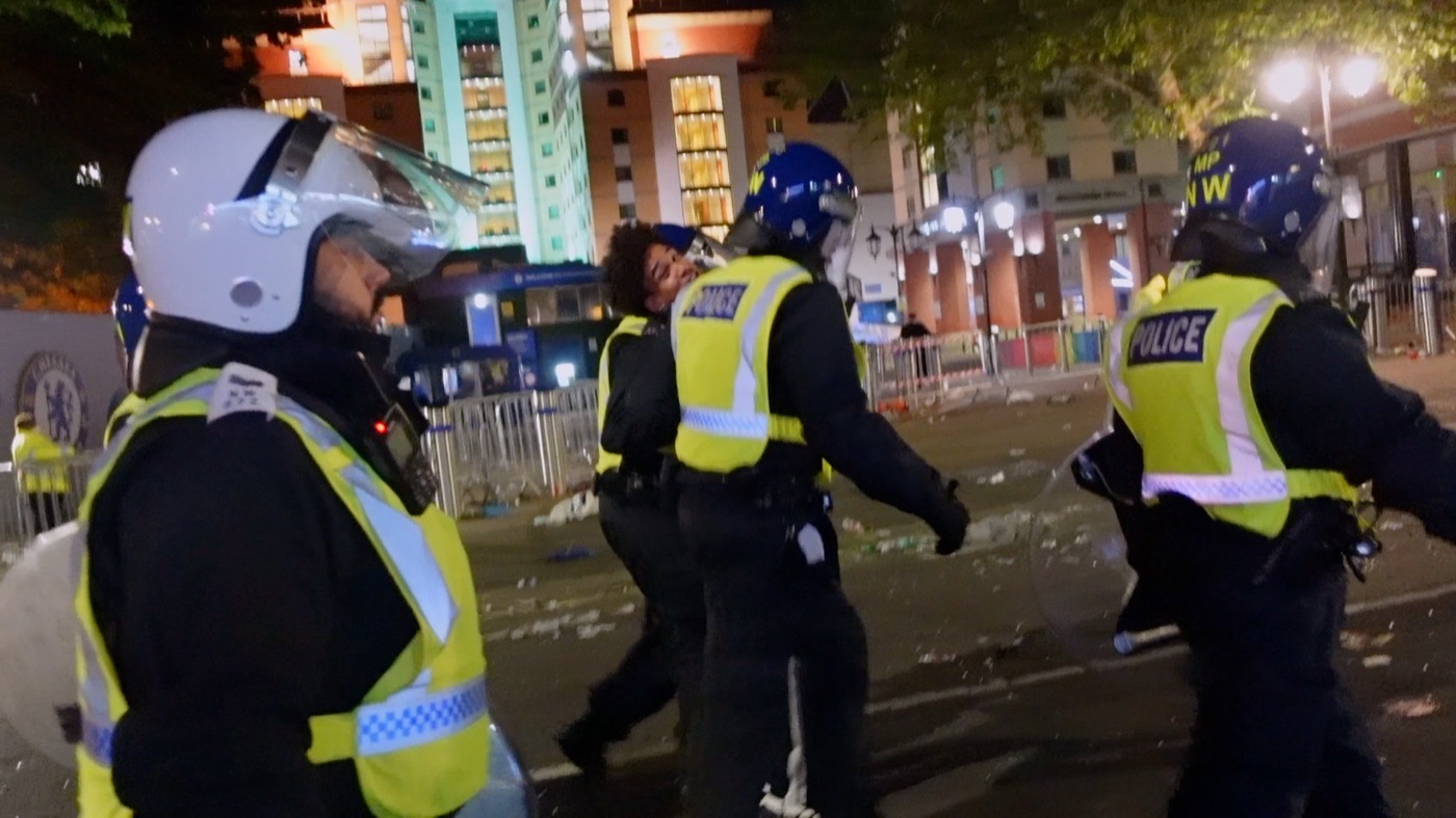 Joshua Arthur turning back toward camera at night, flanked by Metropolitan Police officers, from the documentary Am I Really Free?
