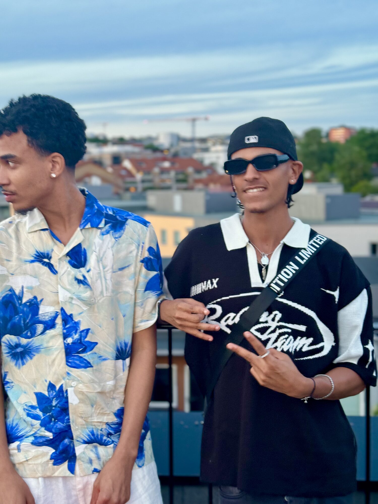 Joshua Arthur (JJDREAMSS) · Oslo · 2024 — Oslo rooftop in summer, floral shirt, looking off-frame beside a friend